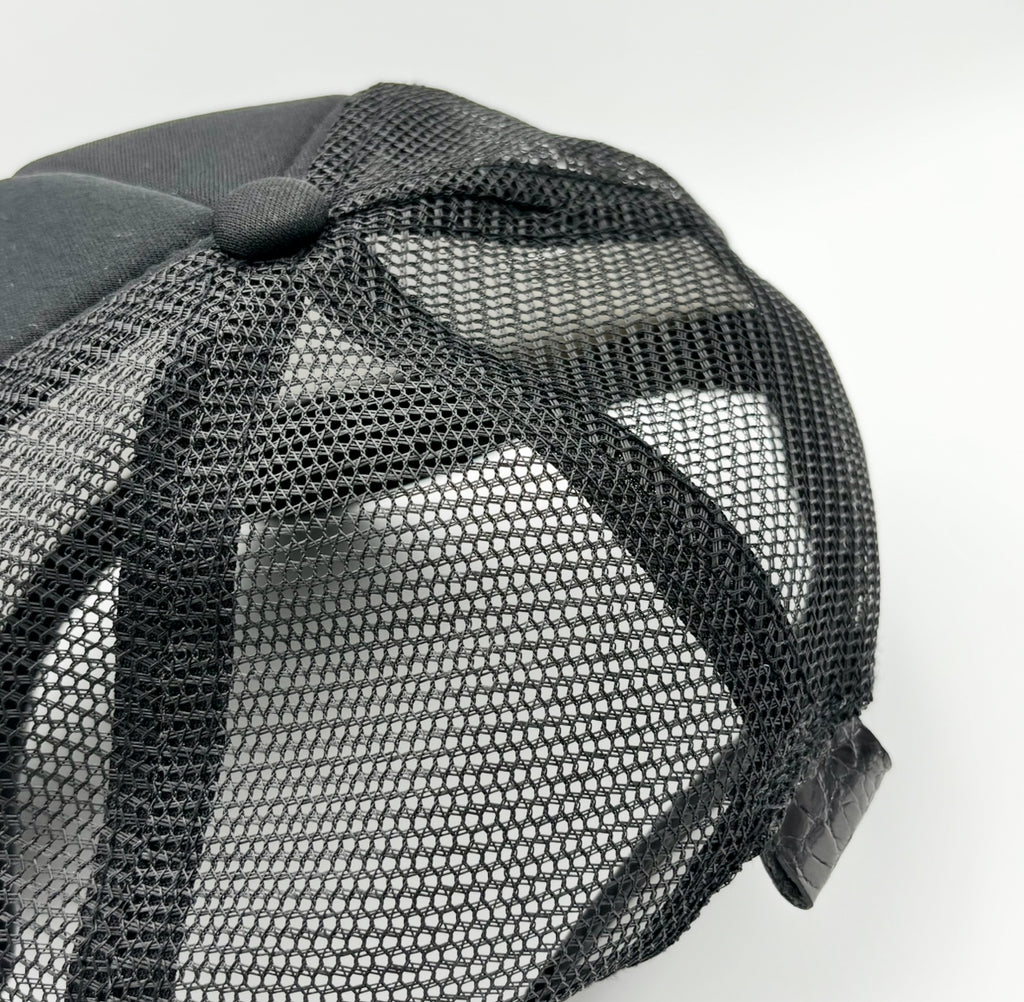 Rear view of black alligator trucker hat showing breathable mesh back and black alligator leather tab