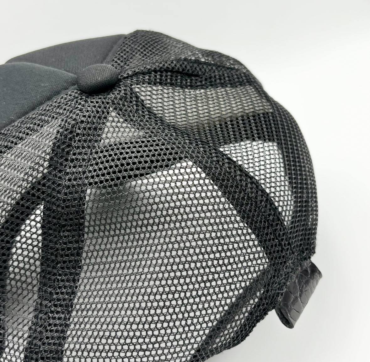 Rear view of black alligator trucker hat showing breathable mesh back and black alligator leather tab