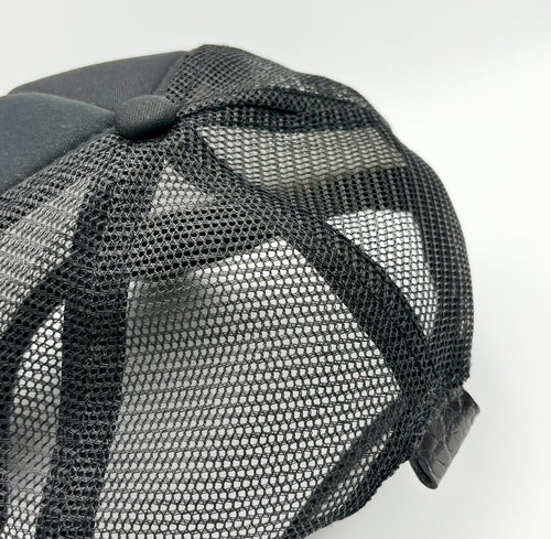 Rear view of black alligator trucker hat showing breathable mesh back and black alligator leather tab