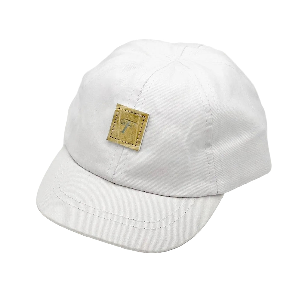 Close-up of glazed natural alligator patch with embossed Frostytch F on white infant cap